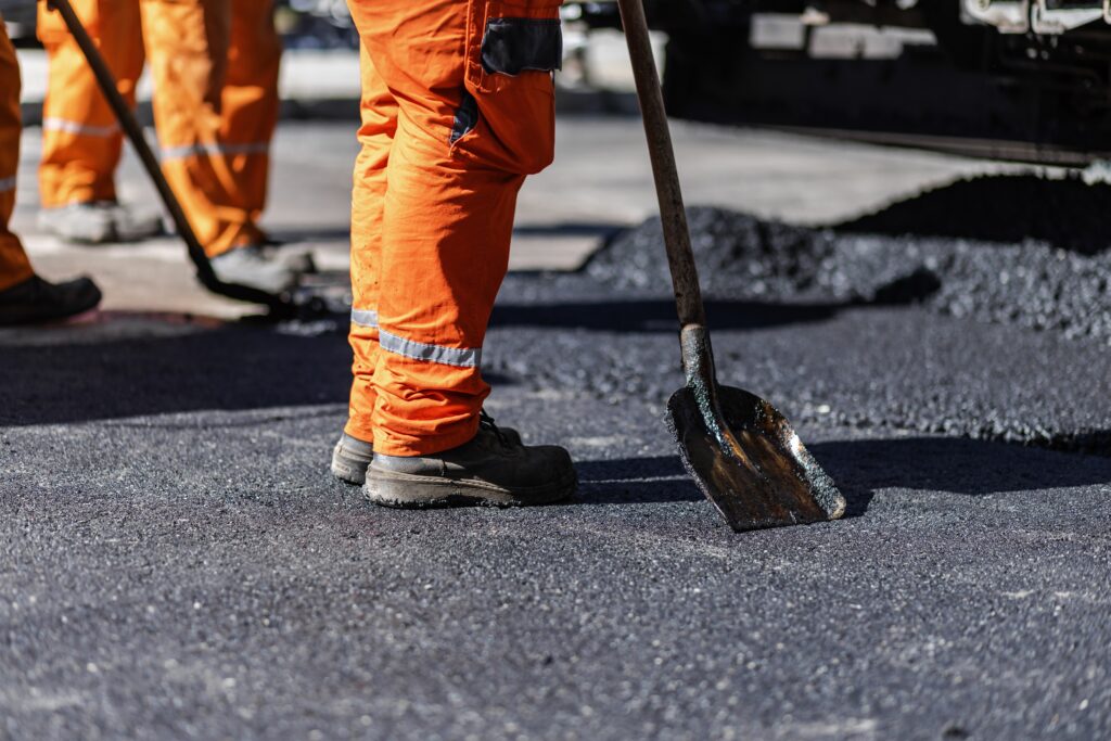 Crew spreading fresh asphalt on a paving project